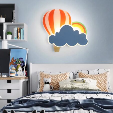 Lámpara de pared con forma de globo aerostático y nube colgada en una pared encima de una cama en el dormitorio de un niño