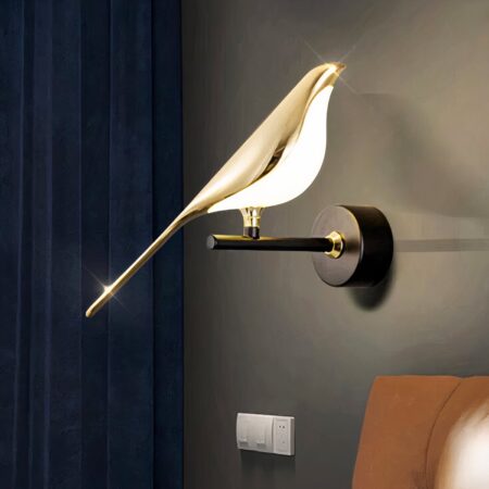 Aplique urraca dorado colgado en una pared negra junto a un cabecero