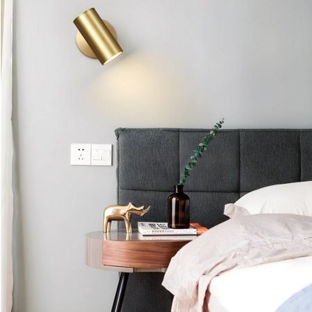 Aplique de tubo dorado con ángulo ajustable colgado en un dormitorio