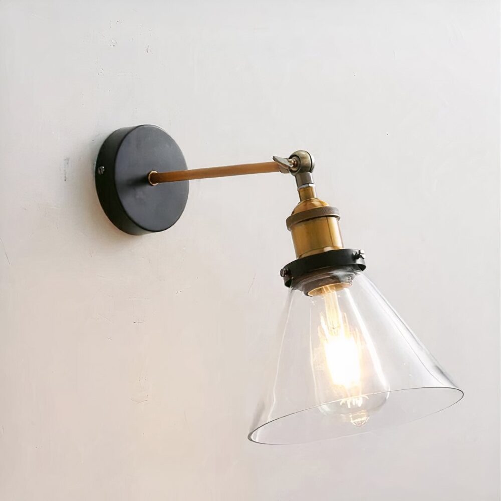 un aplique de estilo industrial con pantalla de cristal transparente se atornilla a una pared gris claro