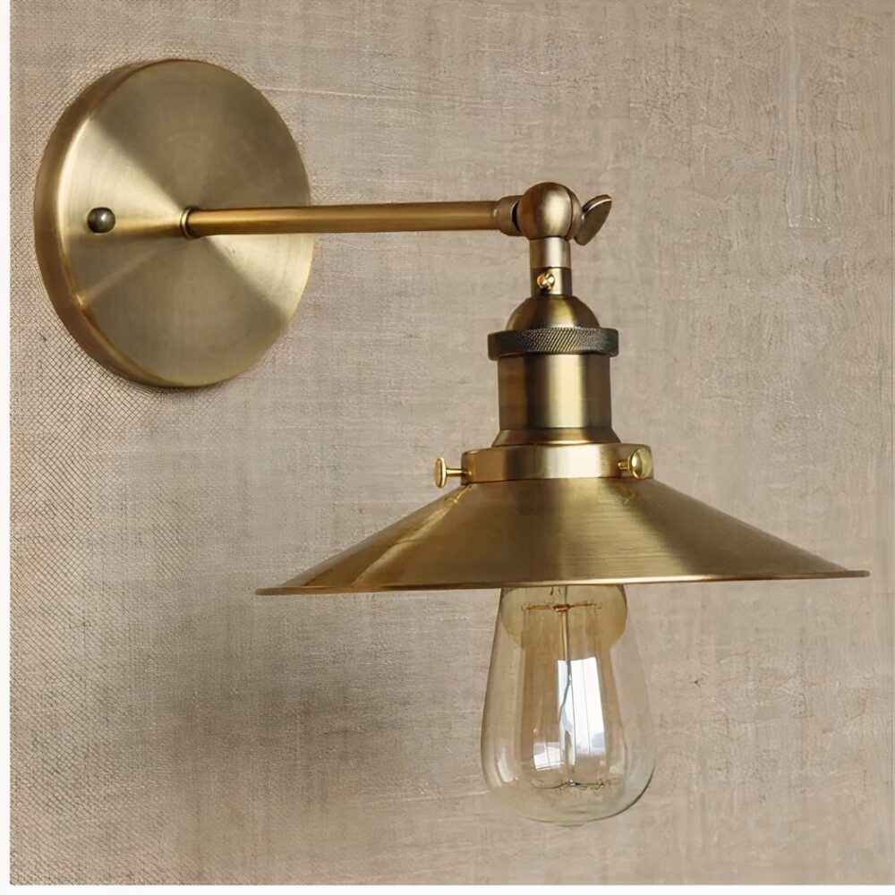 sobre una pared marrón claro se ve un aplique dorado de estilo industrial con una pantalla plana