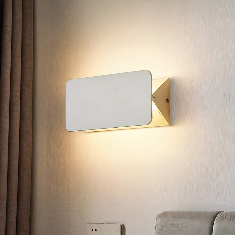 Aplique moderno rectangular de metal blanco con tapa basculante para dirigir la luz. Cortina marrón a la izquierda. Montado en una pared blanca.