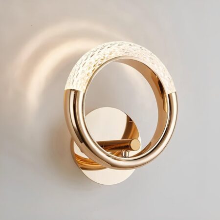 Aplique redondo chapado en oro con un soporte redondo chapado en oro que sujeta un tallo al que se fija un círculo. La parte superior es de acrílico con efecto diamante, el resto es dorado.