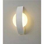 vemos un aplique redondo blanco con una gran placa metálica blanca que lo atraviesa sobre una pared gris claro