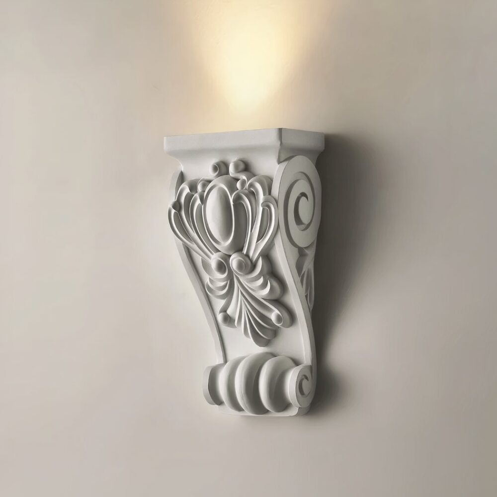 Aplique vintage esculpido en resina, iluminado y colgado en una pared blanca.