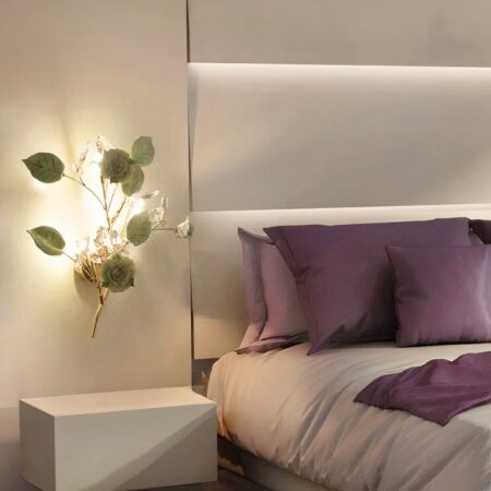 Lámpara de pared con flores de cerámica y luces de cristal bohemio chic en versión verde, colgada en la pared de un dormitorio junto a una cama.