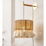 una lámpara de pared de mimbre y flecos de estilo bohemio se ve en una habitación con paredes de color claro