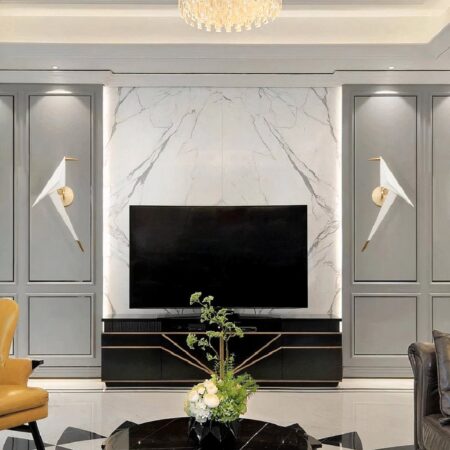 en un salón de paredes grises, un televisor está apagado en el centro y a cada lado hay una lámpara de pared de origami con forma de pájaro blanco