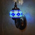 Una lámpara de pared de estilo oriental con una bola de cristal con mosaicos azules montada en una pared