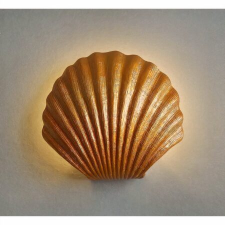 un aplique con forma de concha marina dorada se ve en una pared gris claro