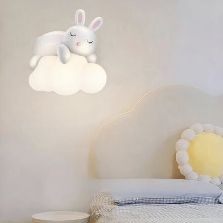 en un dormitorio con una pared gris claro, vemos una lámpara de pared en forma de nube con un conejito durmiendo sobre ella